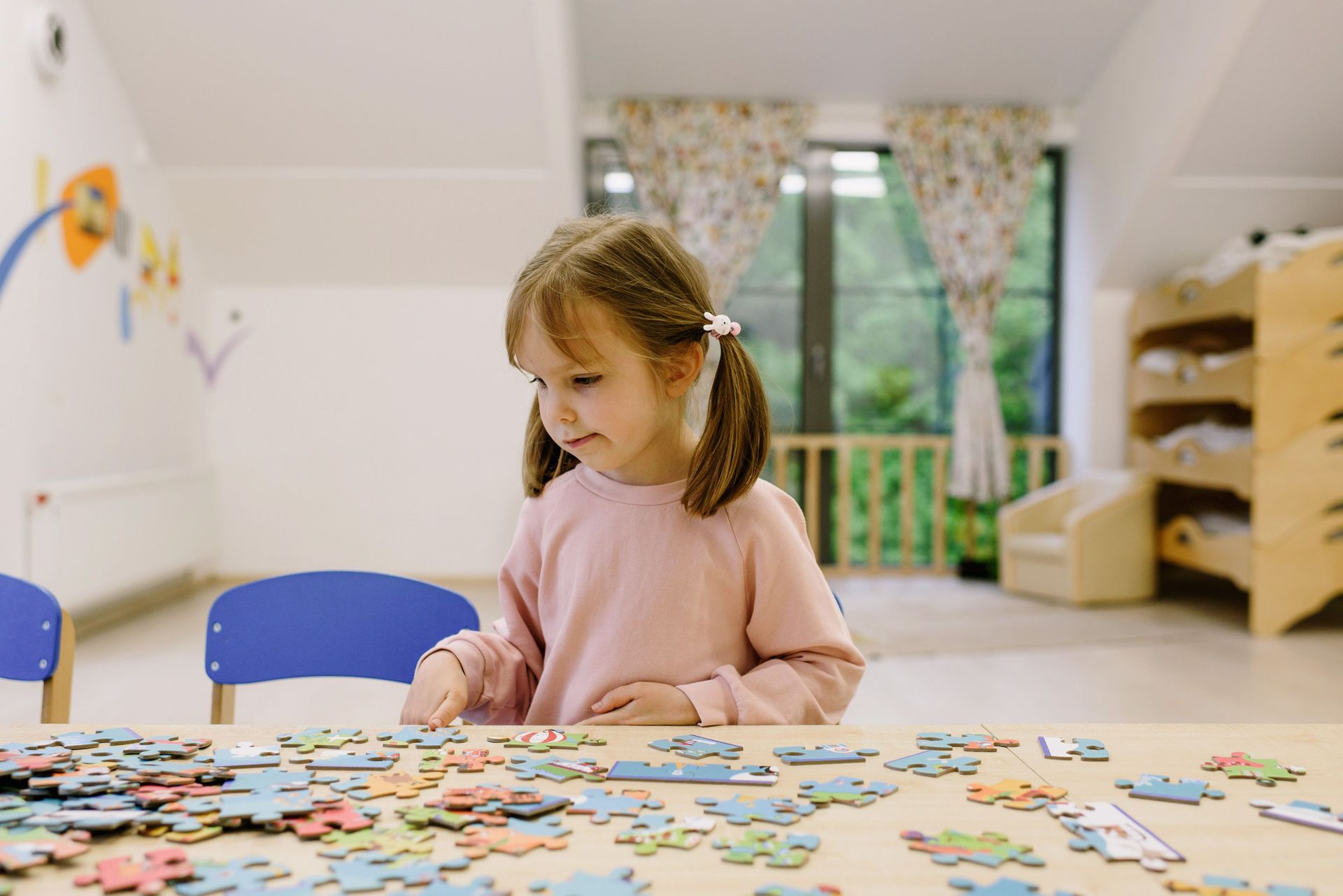 Girl engaged in solving a colorful puzzle at a preschool table.